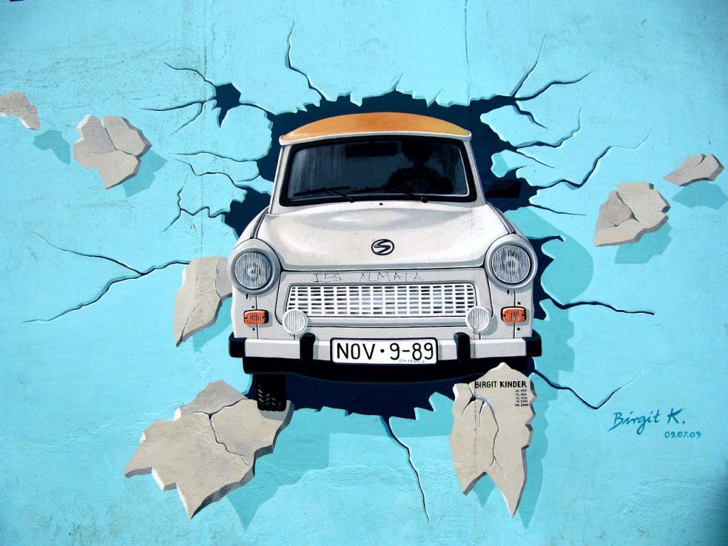 Street art di una trabant, tipica auto tedesca, che rompe il Muro di Berlino